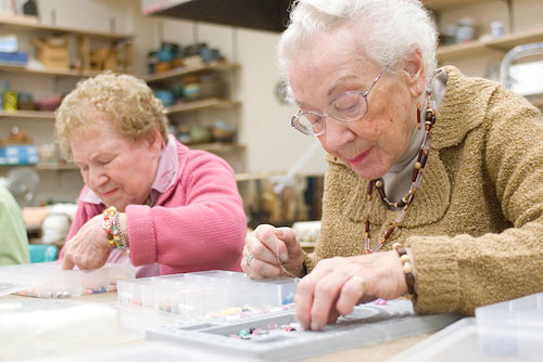 Two residents stringing beads in the creative arts studio