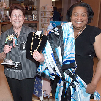 Two volunteers in gift shop showing wares