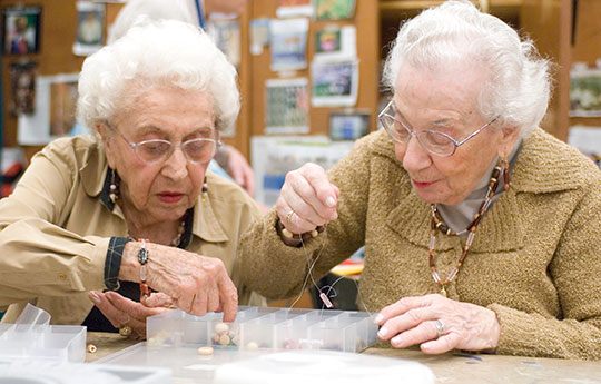 Two residents stringing beads in the creative arts studio