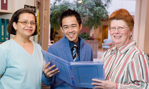 Three staff review a medical chart in the nursing unit
