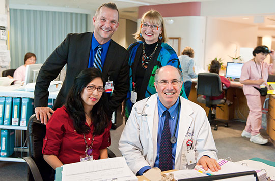 Four staff review a medical chart in the nursing unit